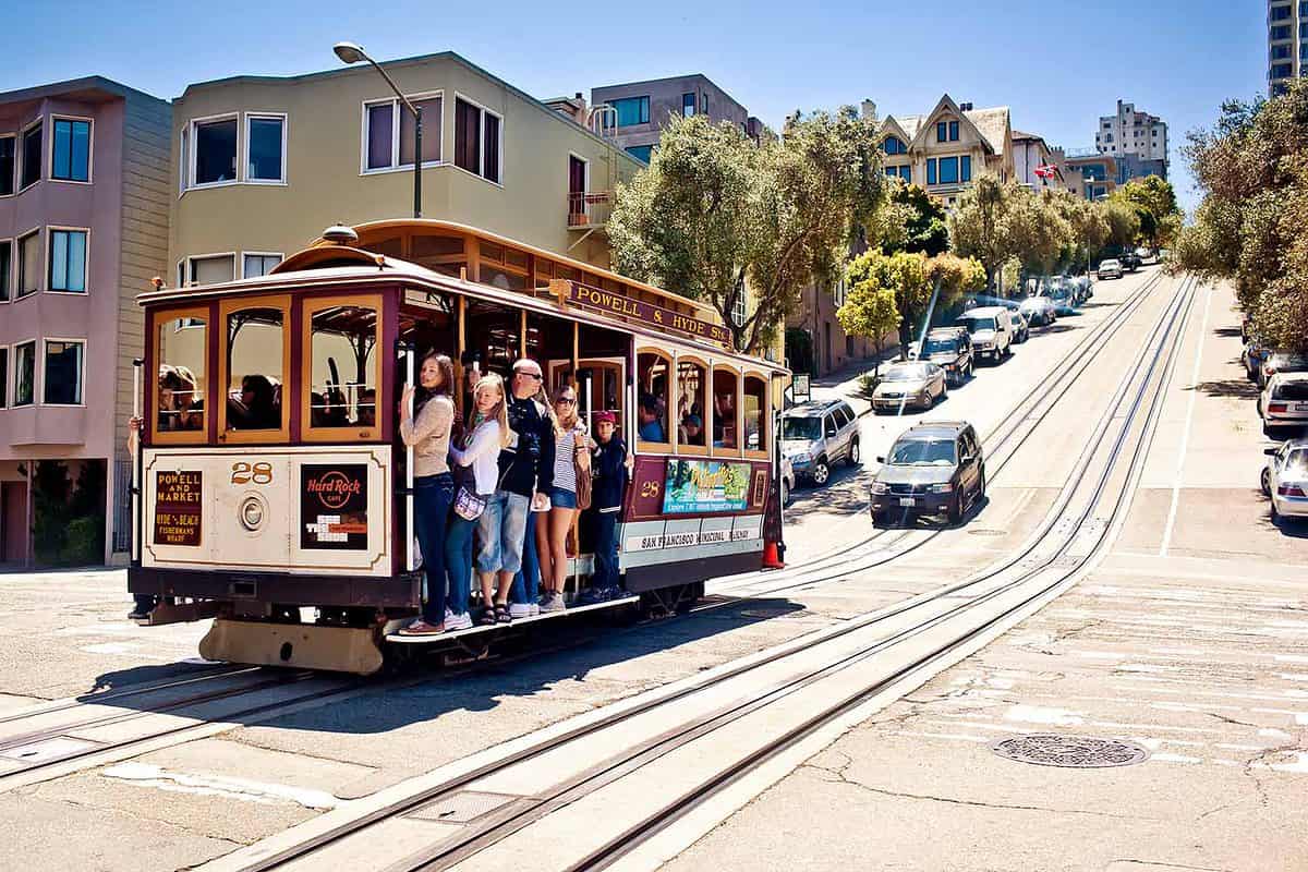 San Francisco Cable Car climbing a steep hill with city buildings in the background